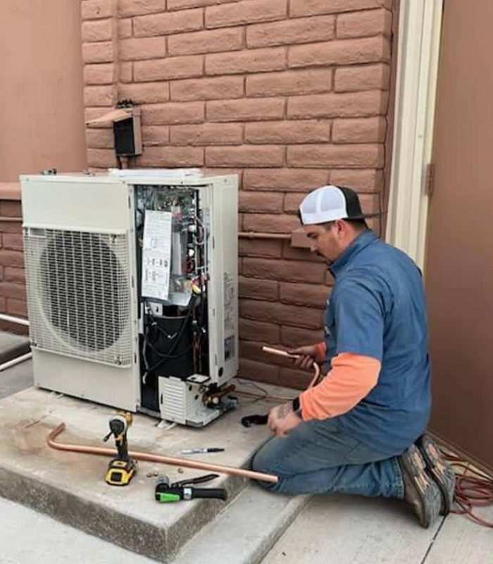 hvac technician fitting pipes to a new air conditioning unit