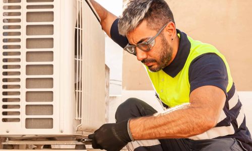 Male technician installing outdoor unit of air conditioner